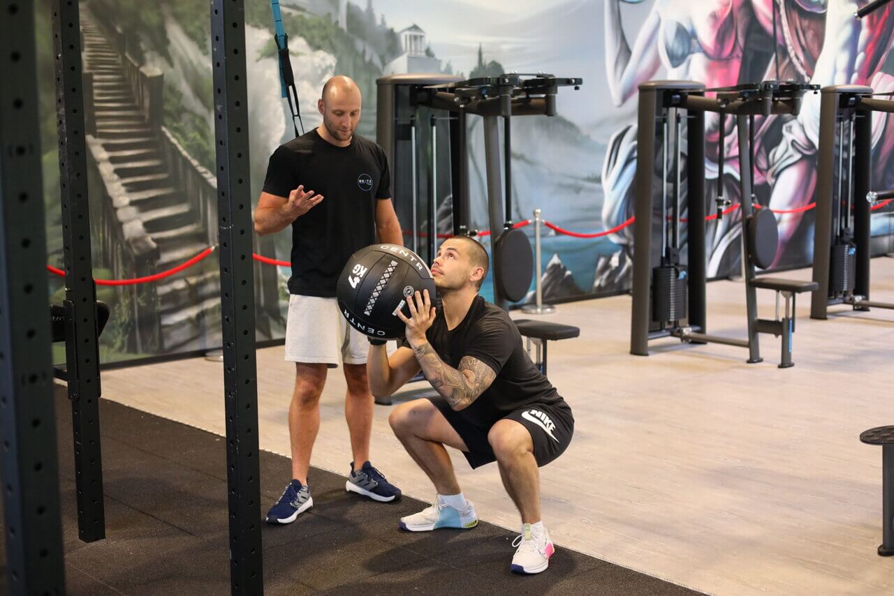 Mitglied trainiert Kniebeugen mit Ball bei BEATZ Fitness